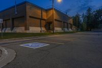 an empty parking lot sits in front of an office building at night in a suburban setting