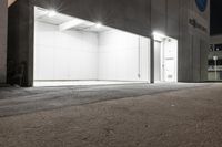 a closed parking garage with lights on at night, outside, and street scene in a commercial city area