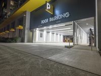 the building is next to the entrance of the parking garage at night or day time