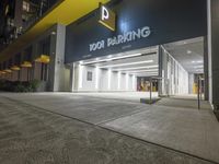 the building is next to the entrance of the parking garage at night or day time