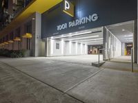 the building is next to the entrance of the parking garage at night or day time