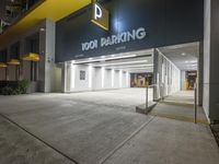 the building is next to the entrance of the parking garage at night or day time