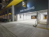 the building is next to the entrance of the parking garage at night or day time