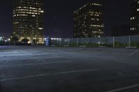 a parking lot is seen at night with multiple tall buildings in the background as seen from the corner of the parking lot