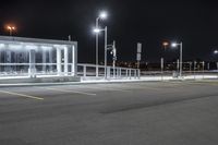 some parking lot with lights and street lights lit up at night time in the foreground