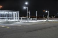 some parking lot with lights and street lights lit up at night time in the foreground