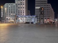 a square in the middle of a large city with people walking on it at night