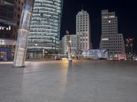 a square in the middle of a large city with people walking on it at night