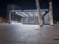 a square in the middle of a large city with people walking on it at night