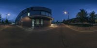 a street view looking up at a road corner with lights in the background and building to the left