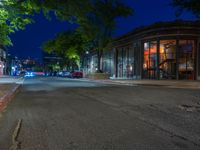 a city street at night with parking meters on either side and the road in the center