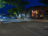 a city street at night with parking meters on either side and the road in the center