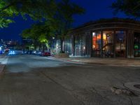 a city street at night with parking meters on either side and the road in the center