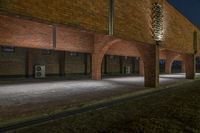 an open courtyard with three brick archways lit up at night with street lights on