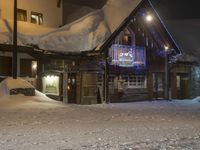 a building is in the snow outside a ski resort at night, with light lite up