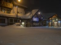 a building is in the snow outside a ski resort at night, with light lite up