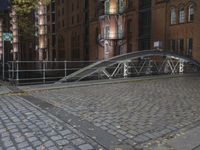 a street bridge that is over some buildings on a street at night, with some leaves all around the walkway