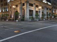 a street with a light at the corner and a building to the side and some lights above the street