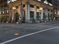 a street with a light at the corner and a building to the side and some lights above the street