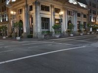 a street with a light at the corner and a building to the side and some lights above the street