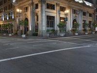 a street with a light at the corner and a building to the side and some lights above the street