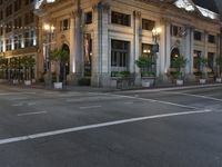 a street with a light at the corner and a building to the side and some lights above the street