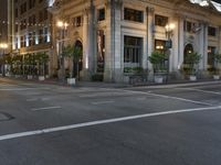 a street with a light at the corner and a building to the side and some lights above the street