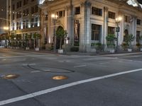 a street with a light at the corner and a building to the side and some lights above the street