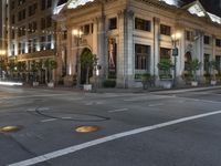 a street with a light at the corner and a building to the side and some lights above the street