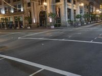 a street with a light at the corner and a building to the side and some lights above the street