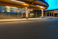 a street near an airport at night with lights on the buildings and blue glass windows