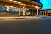 a street near an airport at night with lights on the buildings and blue glass windows