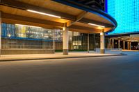 a street near an airport at night with lights on the buildings and blue glass windows