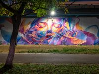 an urban scene that appears to be filled with graffitis and people and trees with the lights on