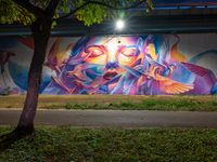 an urban scene that appears to be filled with graffitis and people and trees with the lights on