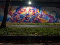 an urban scene that appears to be filled with graffitis and people and trees with the lights on