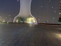 a clock tower in a building at night in an empty space, with buildings in the background