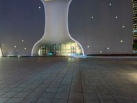 a clock tower in a building at night in an empty space, with buildings in the background