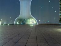 a clock tower in a building at night in an empty space, with buildings in the background