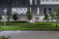 a courtyard area at night with a fire hydrant and green lawn surrounded by trees