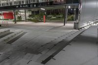 an empty walkway lined with steps leading to a building at night time as seen from above