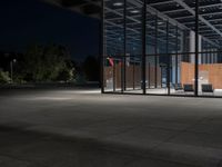 a concrete floor at night with lights on it, and chairs on the side of it