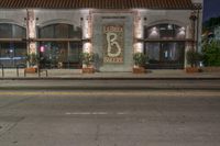 an empty city street with a brick building at night, and the words, 66, in front of it