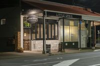 a street at night with a cafe in the corner and a bus coming out of it