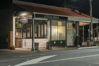 a street at night with a cafe in the corner and a bus coming out of it