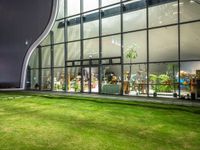 grassy area with glass window and green yard by night of open space in front of building