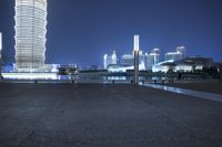 a night view of a city skyline with skyscrapers and buildings in the background from a bridge over water