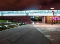 a walkway outside of a building with a lighted walkway leading into it at night and several lights at night