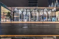 a bus stop with lights that are on and some buildings in the background at night