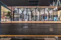 a bus stop with lights that are on and some buildings in the background at night